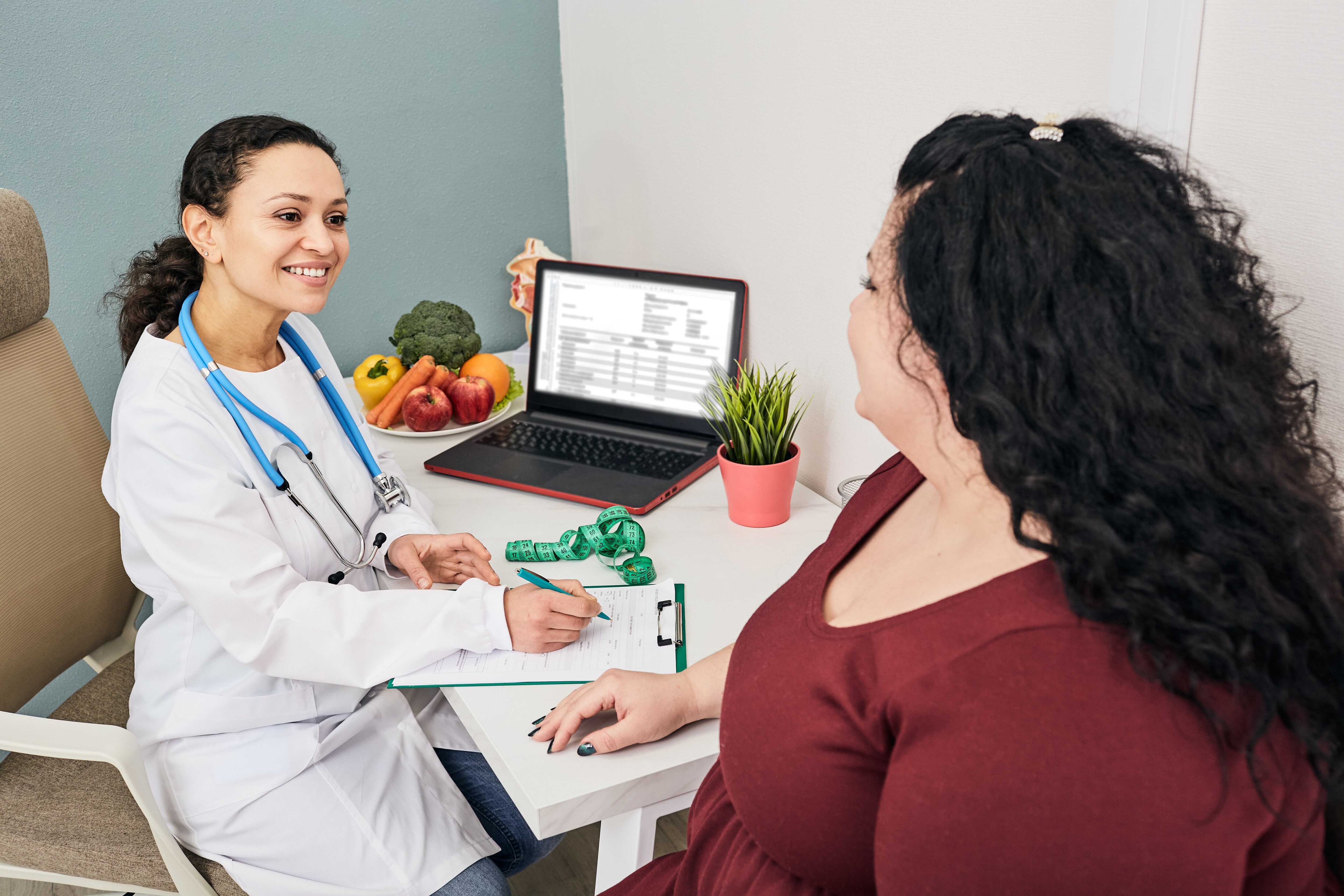 Doctor talking to woman in clinic with fruits and vegetables.